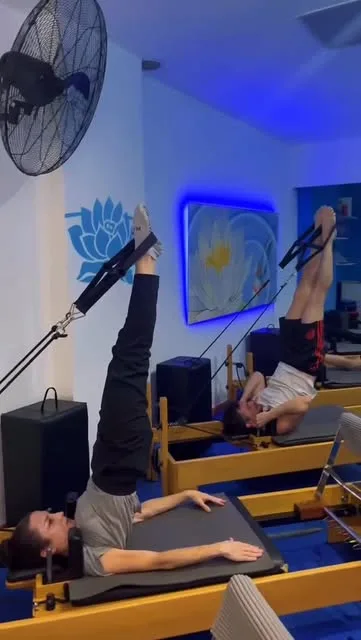 Alumnas haciendo un ejercicio con las piernas arriba en reformers, con la luz azul del salón