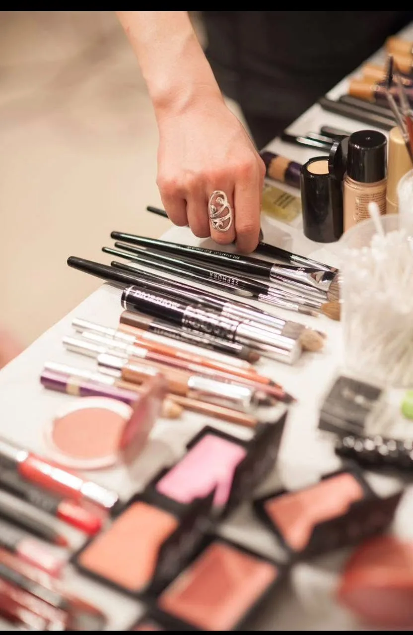 Mesa con paletas de rubor, labiales, pinceles y delineadores de maquillaje profesional