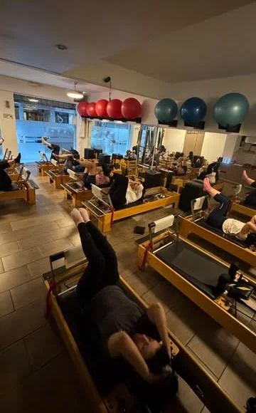 Salón de Soul Pilates con una fila de reformers de madera, pelotas azules y rojas en la pared y ventanal a la calle