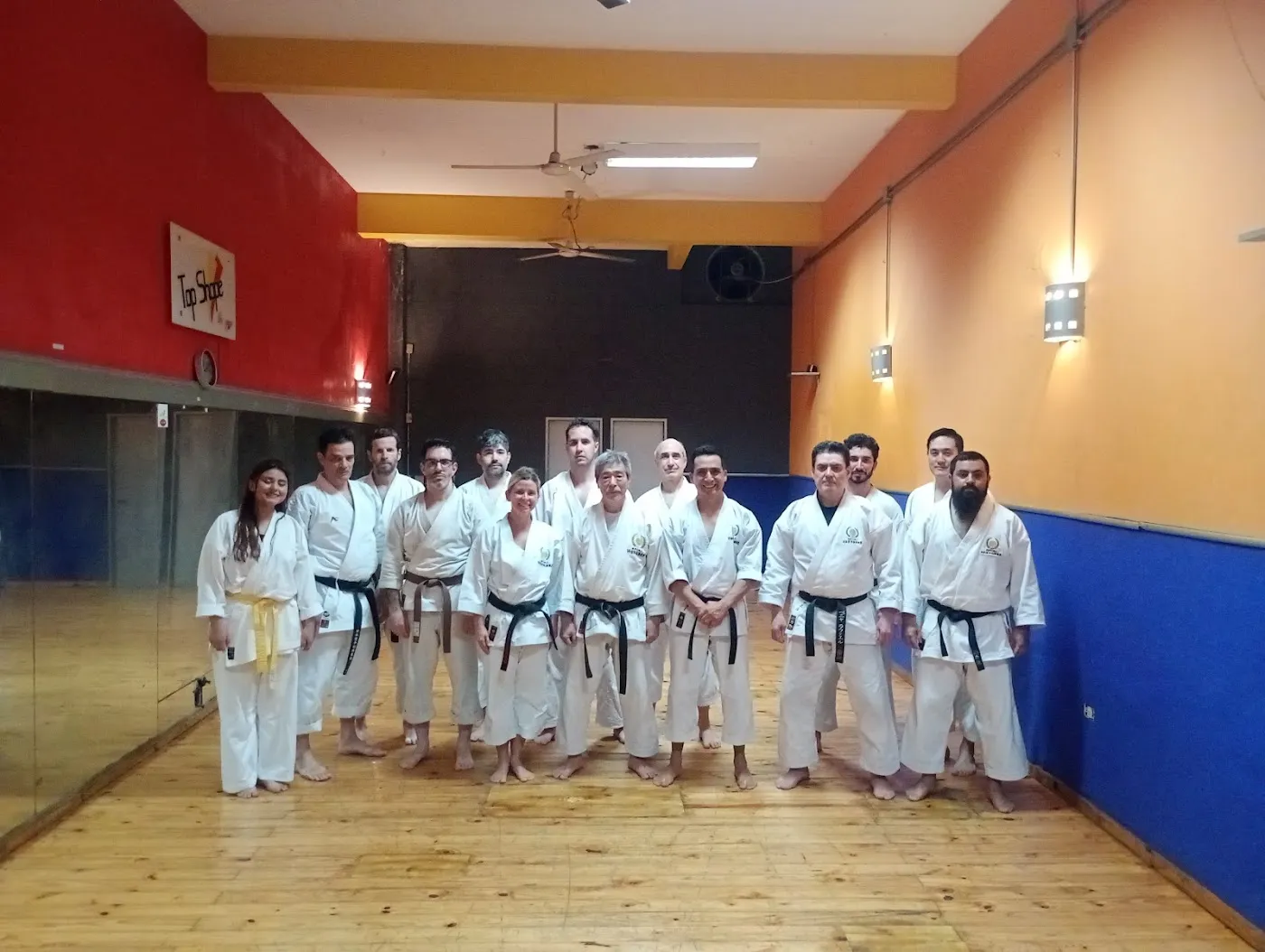 Grupo de alumnos de karate con sus cinturones en el salón