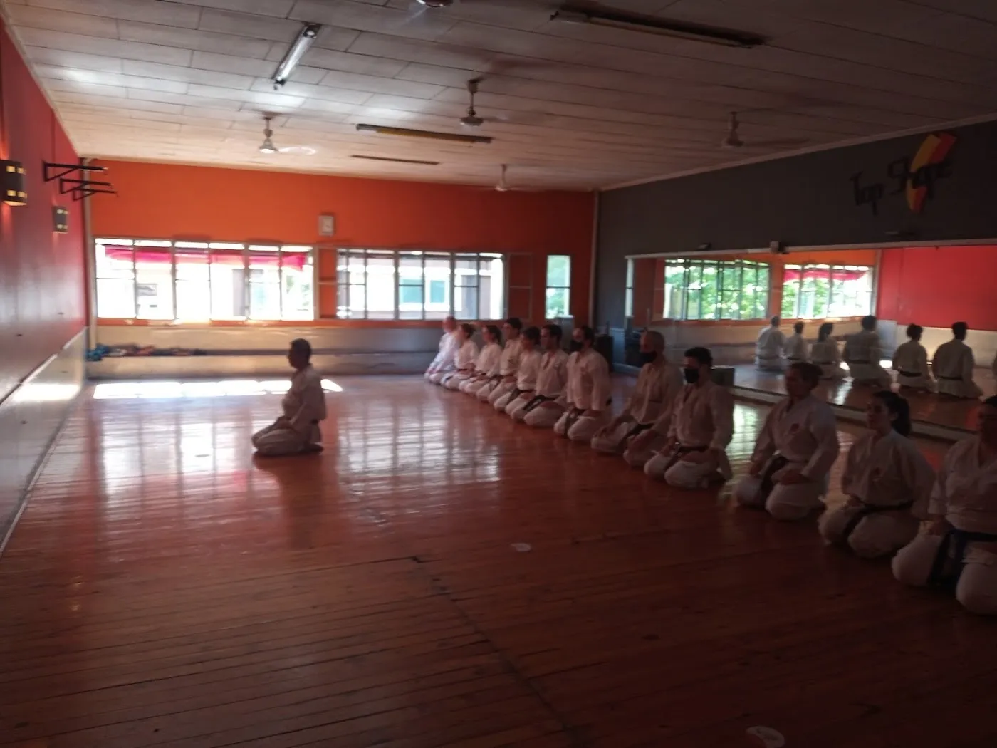 Alumnos de karate sentados en fila sobre el piso de madera